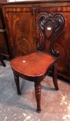 A pair of William IV mahogany hall chairs, with carved scroll backs with shield,