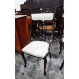 A pair of Edwardian stained as mahogany chairs with fruit and foliate carved crest padded crest