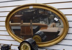 An oval bevelled plate mirror in gilt moulded frame,