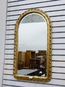 A modern wall mirror within a pierced moulded arched frame