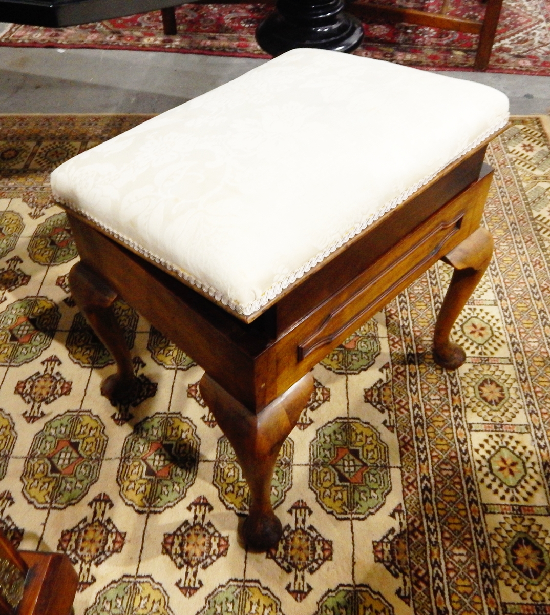 A walnut rectangular top piano stool, the rising top enclosing storage space,