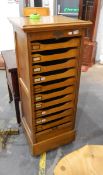 An early twentieth century pale oak filing cabinet, fitted with sliding trays,