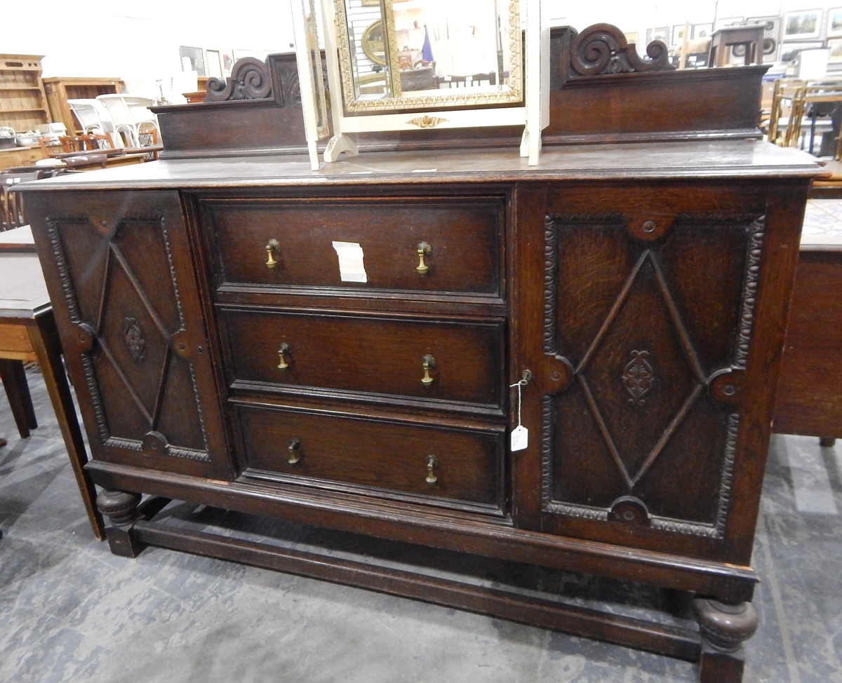 A circa 1920's oak sideboard with egg and dart and geometric panelled doors flanking three central