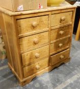 A 19th century pine chest of eight short drawers, on shaped bracket feet, with bun handles,