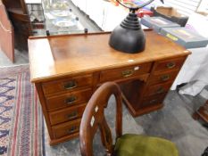 An Edwardian mahogany kneehole pedestal desk having an arrangement of nine drawers,