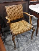 A cane panelled beech framed elbow chair on cabriole supports
