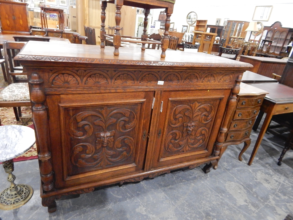 An Edwardian oak sideboard having carved lunette ornamentation and enclosed by two carved panel