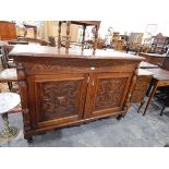 An Edwardian oak sideboard having carved lunette ornamentation and enclosed by two carved panel