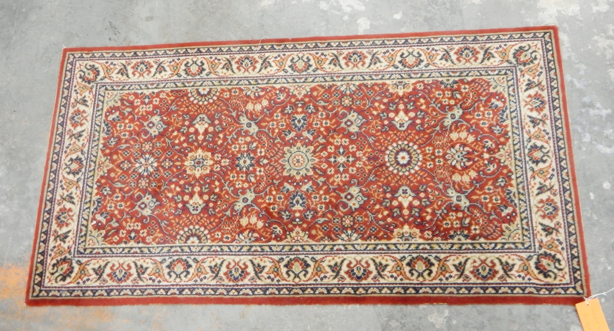 A Persian style rug with red ground, cream borders, decorated with floral pattern,