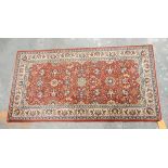 A Persian style rug with red ground, cream borders, decorated with floral pattern,