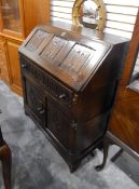 An oak reproduction Jacobean style bureau, the fall with three linenfold panels,