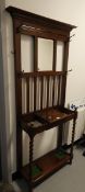 An oak hall stand with mirror back and brass coat hooks, on spirally twisted legs,