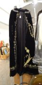 A full-length black velvet cape with applied gold thread decoration