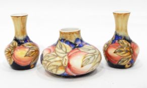 A pair of vases with tube lined decoration, of berries and fruit in the Moorcroft style,