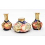 A pair of vases with tube lined decoration, of berries and fruit in the Moorcroft style,