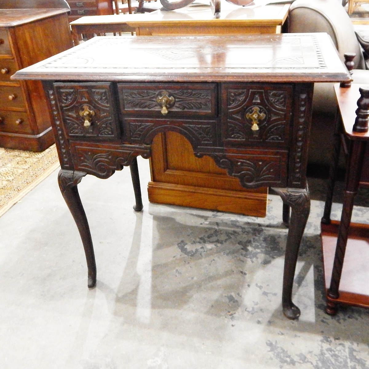 A Georgian style carved oak lowboy, with moulded edge top, three frieze drawers above shaped apron,