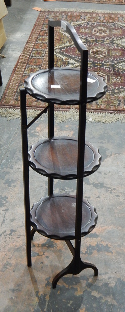 A three-tier cakestand on shaped feet (handle damaged)