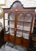 An Edwardian mahogany veneered china display cabinet enclosed by glass panelled doors and on