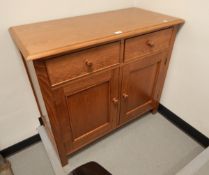 A modern oak sideboard with two short drawers, cupboard underneath, on block supports,