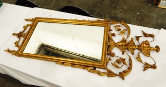 A gilt moulded mirror surmounted by floral decoration