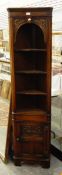 A small oak double corner cupboard, with open shelves in the upper section and panelled door below,