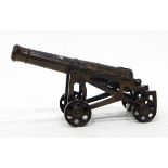 A miniature bronze model of a cannon with integral wheeled base,