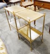 A pair of gilt metal two shelf side tables, with inset leather tops, on turned legs with castors,