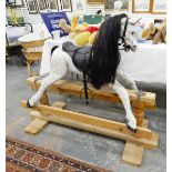 A modern wooden rocking horse, the dappled grey horse with saddle and stirrups,