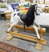 A modern wooden rocking horse, the dappled grey horse with saddle and stirrups,