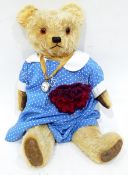 A vintage mohair bear with glass eyes with a fob watch attached