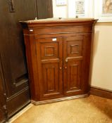 Early 19th century fruitwood hanging corner cupboard enclosed by a pair of panelled doors,