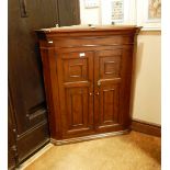 Early 19th century fruitwood hanging corner cupboard enclosed by a pair of panelled doors,