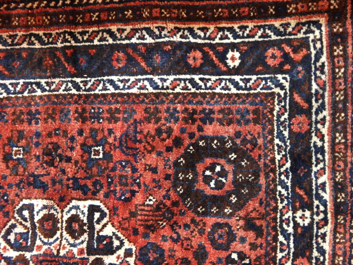 Persian style wool rug with pink ground and floral and geometric decoration, black borders,