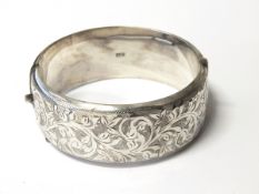 Silver hinged bangle with engraved foliate scroll decoration,
