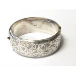 Silver hinged bangle with engraved foliate scroll decoration,