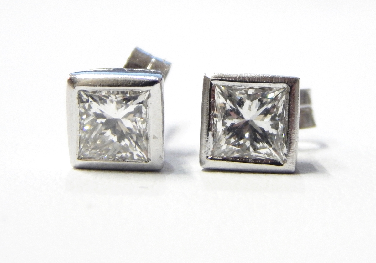 Pair of 18ct white gold princess cut earrings, each rub-over set, approx. .