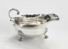 George VI silver sauce boat, oval with cut card borders, free scroll handle, three hoof feet,