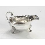 George VI silver sauce boat, oval with cut card borders, free scroll handle, three hoof feet,