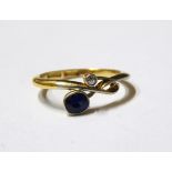 Sapphire and diamond crossover ring, the oval mixed cut sapphire set opposite an eight cut diamond,