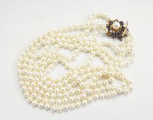 Three-row necklace of uniform cultured pearls by Mikimoto with gold flowerhead clasp set with