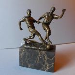 A bronze figure group of footballers in play raised on a marble base.