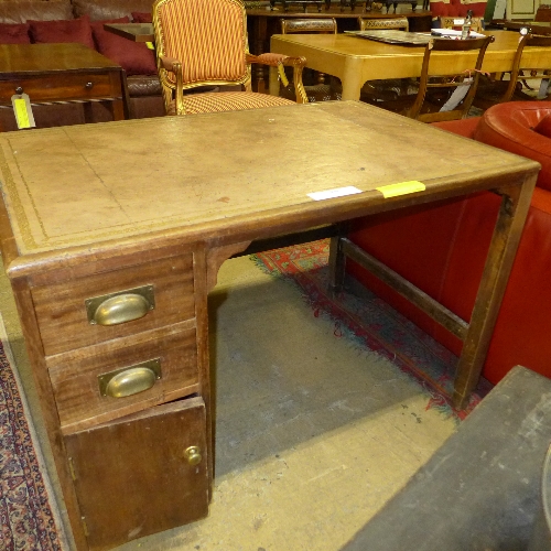 An early 20th Century oak desk, the brown tooled leather top over single pedestal and stretchered