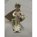 An English porcelain figure of a standing cherub holding a basket of flowers