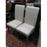 A set of six contemporary dining chairs in cream faux leather upholstery on beech wood supports.