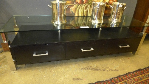 A contemporary low chest the glass rectangular top over chrome stretchered supports and ebonised