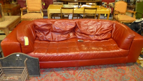 A contemporary Italian designer red leather three seater sofa stamed 'U' the curved back over