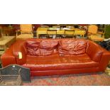 A contemporary Italian designer red leather three seater sofa stamed 'U' the curved back over