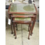 An early 20th Century carved mahogany nest of three tables, the tooled leather tops over cabriole