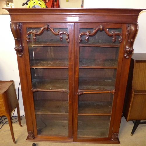 A late 19th Century Victorian mahogany bookcase, the cornice above glazed doors enclosing shelves