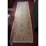 A hand knotted Pakistani woolen runner the beige and orange field decorated with flowerhead motifs